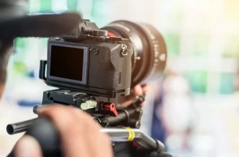 Videographer takes video camera with blank screen Videographer takes video camera with blank screen and blur image of group people in the background with free copy space for your text